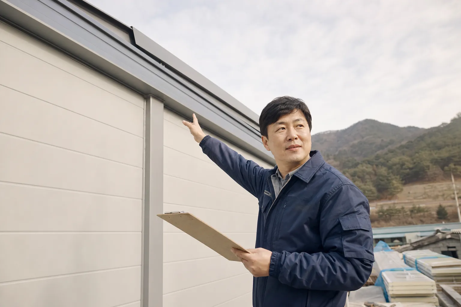판넬 창고 앞에서 현장 점검표를 확인하는 시공 담당자